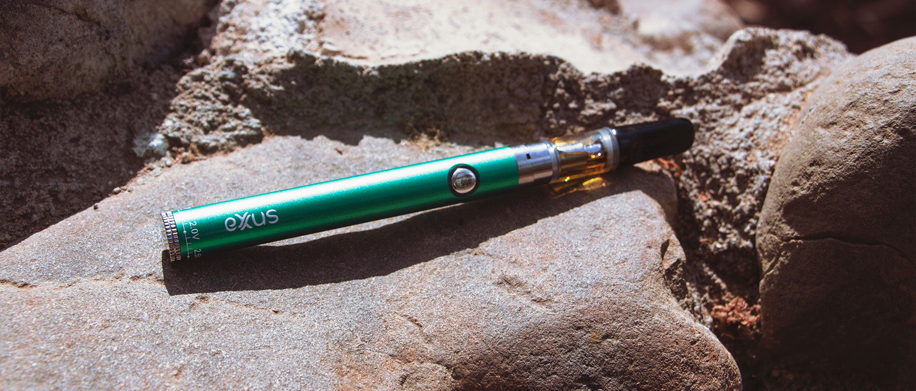 Exxus Twistr Battery with oil cartridge laying on rock outside on a sunny day