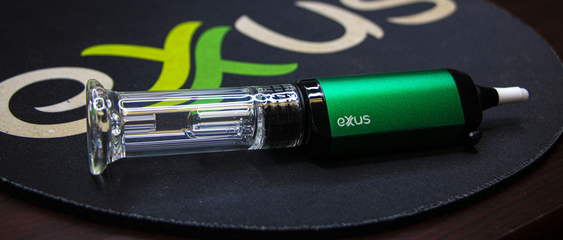 Green Exxus VRS Nectar Collector Concentrate Vaporizer laying down on mouse pad with Exxus Logo